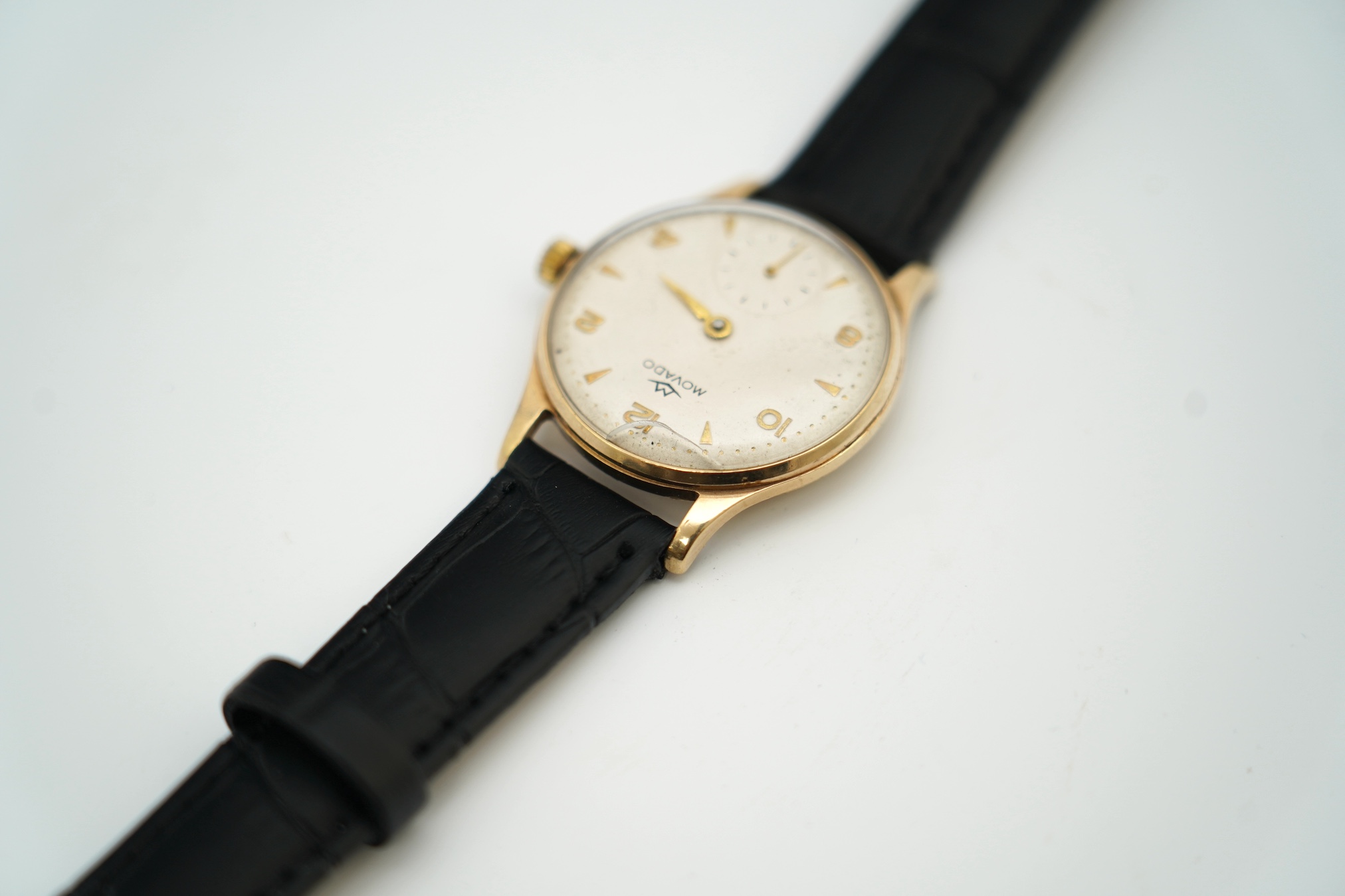 A gentleman's 9ct gold Movado manual wind wrist watch, with baton and Arabic numerals, on associated leather strap, case diameter 32mm. Condition - poor